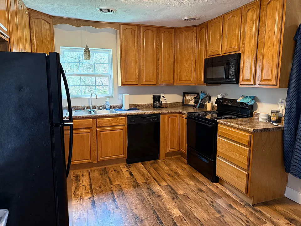 Kitchen with refrigerator, dishwasher, range and over the range microwave hood.