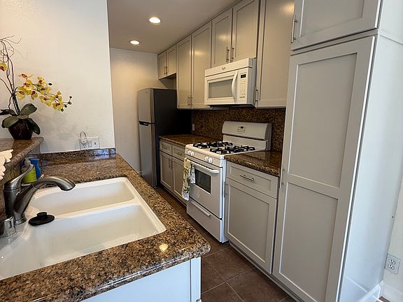 Kitchen with stove, dishwasher, microwave and refrigerator. Granite countertops.