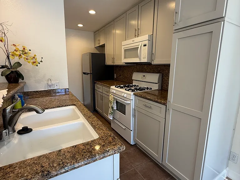 Kitchen with stove, dishwasher, microwave and refrigerator. Granite countertops.