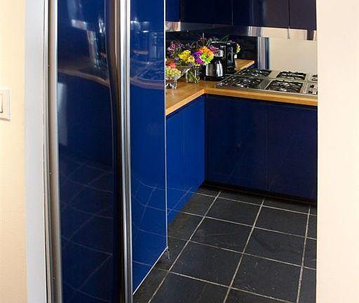 Custom designed Yves Klein blue kitchen with black slate floor and high-tech lowered ceiling hiding ventilation and lights.