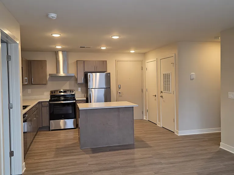 Large open kitchen with island. Includes dishwasher, range, architectural hood vent, microwave cabinet, refrigerator, garbage disposal, large modern sink and faucet.