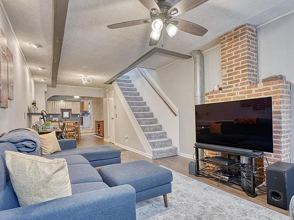 Ample living room with space for full size sofa in front of an exposed bring mantle.