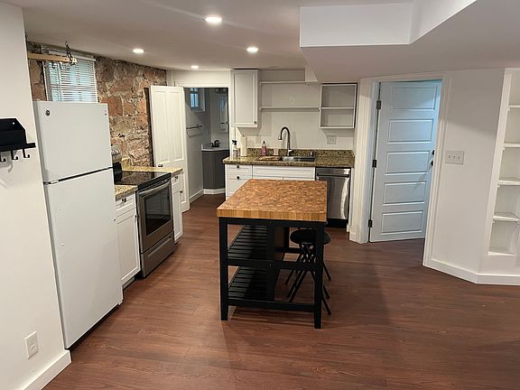 Kitchen. Door left of the island is to the bathroom, door right of the island is to the laundry room, and hallway to the far right goes to the bedrooms