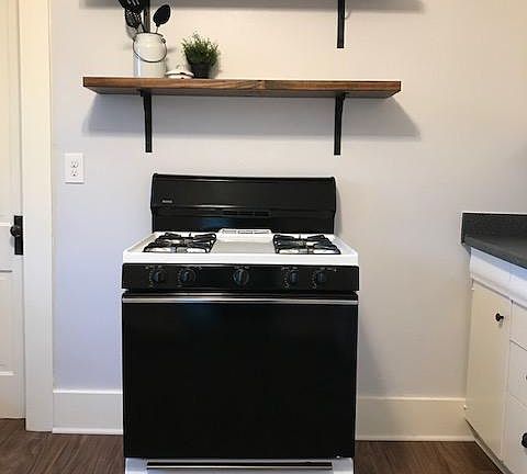 Gas stove with open shelving in spacious kitchen.