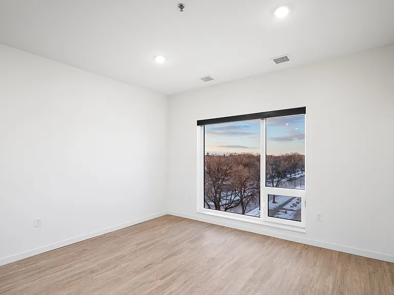 Bright, spacious room with elegant wooden flooring and a large window offering scenic outdoor views, perfect for creating a cozy living space. Bright, spacious room with elegant wooden flooring and a large window offering scenic outdoor views, perfect for