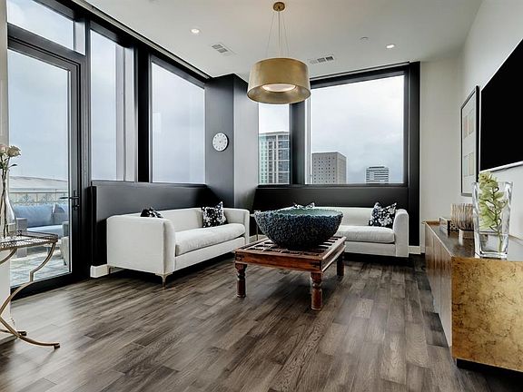 The open living room features 10 foot ceilings, electronic privacy and blackout motarized shades with wall mounted controls, upgraded chandelier and Samsung Frame TV ($1000 negotiable)