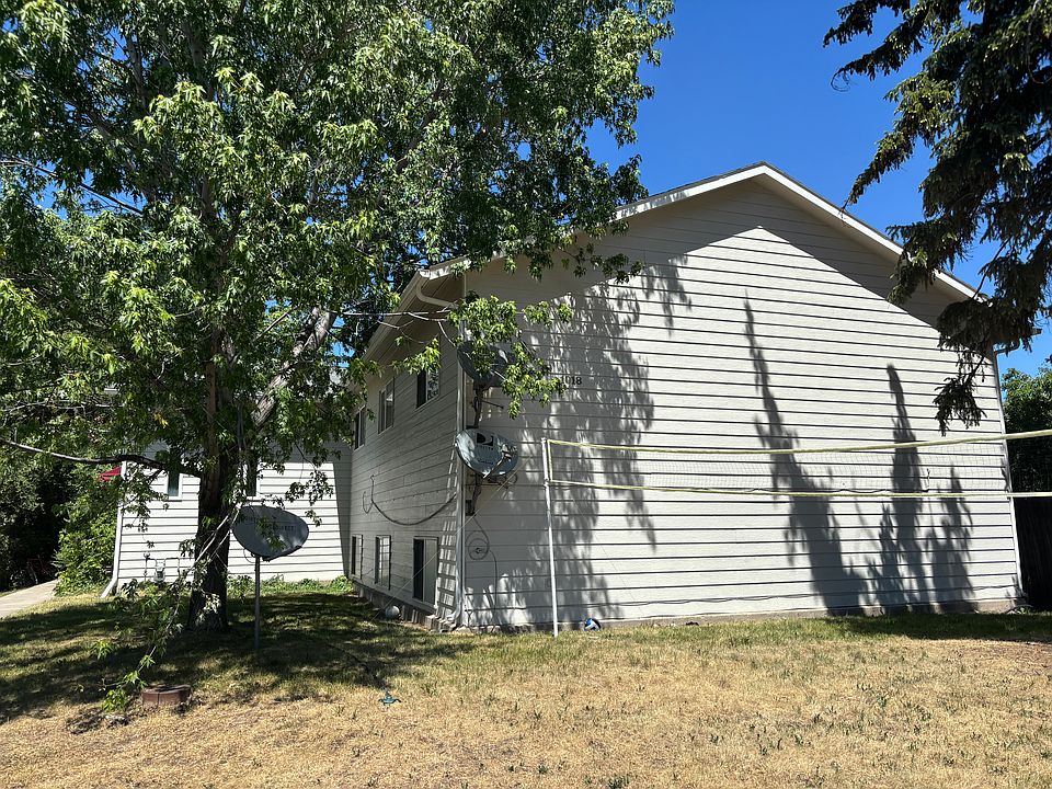 Street view of property featuring a wide lawn and large trees.