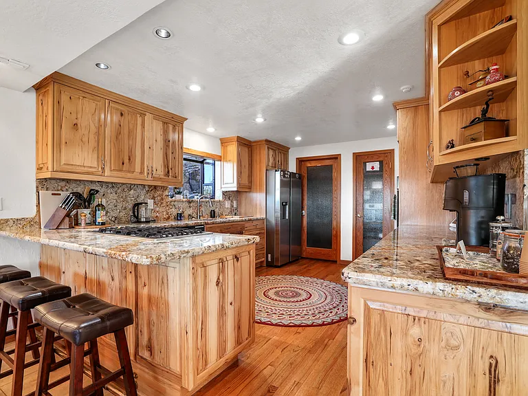 A chef's kitchen with island, dishwasher, double ovens, stovetop and refrigerator and freezer.