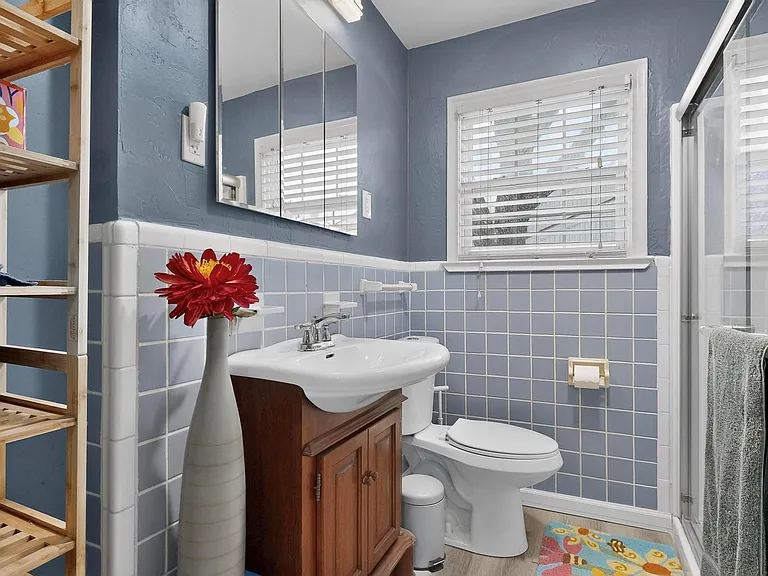 A bright bathroom with a modern vanity, toilet, and shower stall