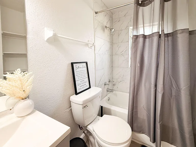 Full bathroom with tub/shower combo, tile surround, and built-in towel bar for everyday convenience.