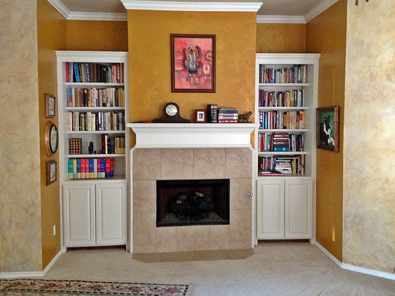 Living room has bookshelves, cabinets, and gas log fireplace