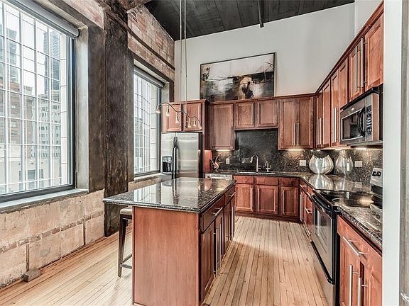 Impressive Kitchen with cherry stained cabinetry, granite counters & backsplash, SS appliances, great Pantry & island with breakfast bar. 2 large windows fill the Kitchen with light! This is not your typical tiny condo Kitchen!