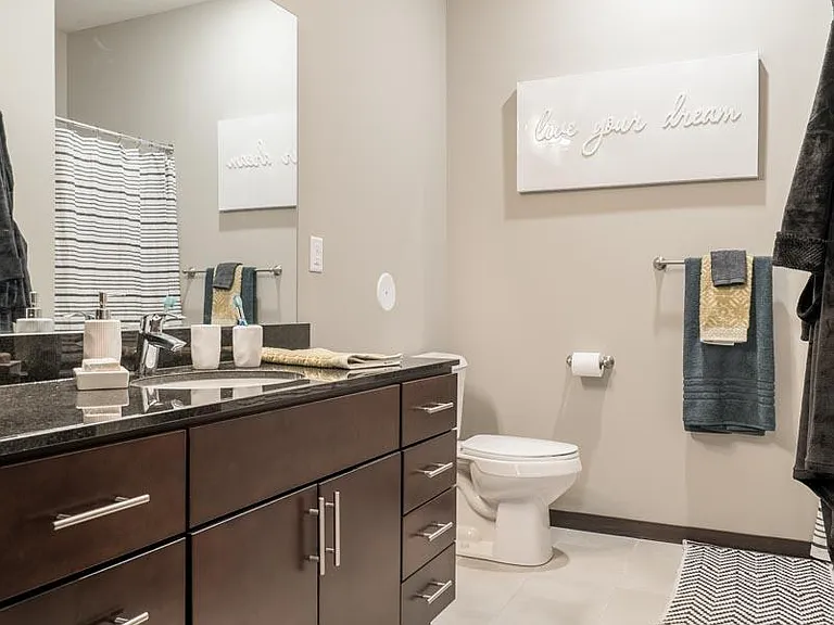 Our traditional design scheme features light tile in the bathrooms with dark cabinetry and granite countertops.