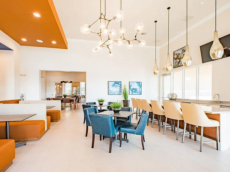 Resident lounge with dining tables, kitchenette, and bar seating
