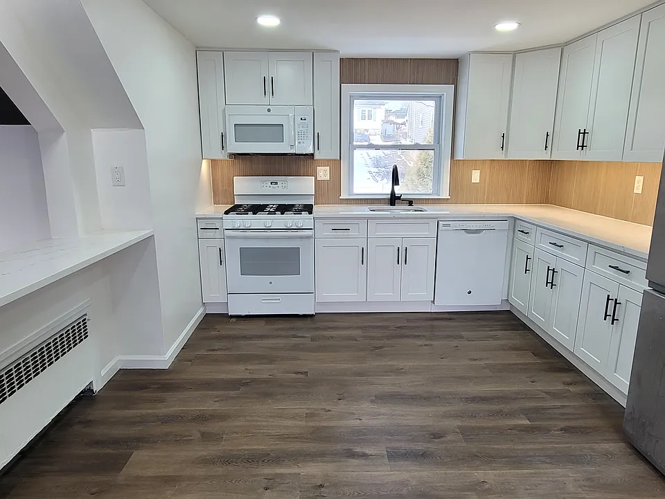 New white shaker cabinets, quartz countertops, tiled slat backsplash, black fixtures