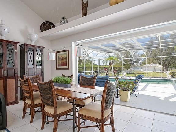 Dining room opens up to a sitting area outside and pool with a view of the stable, paddocks, and pond.