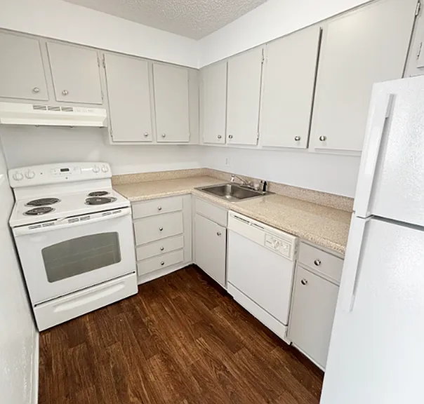 Bright and inviting kitchen with modern white cabinets, sleek appliances, and elegant wood flooring.