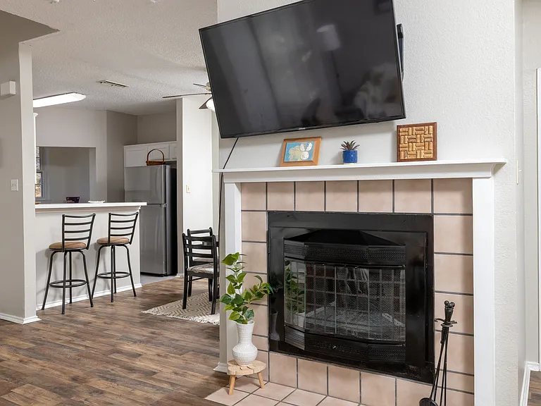 Cozy, spacious living room featuring a comfy couch, two chairs, a warm fireplace, TV, and a bookshelf stocked with books and games_perfect for relaxing or entertaining.