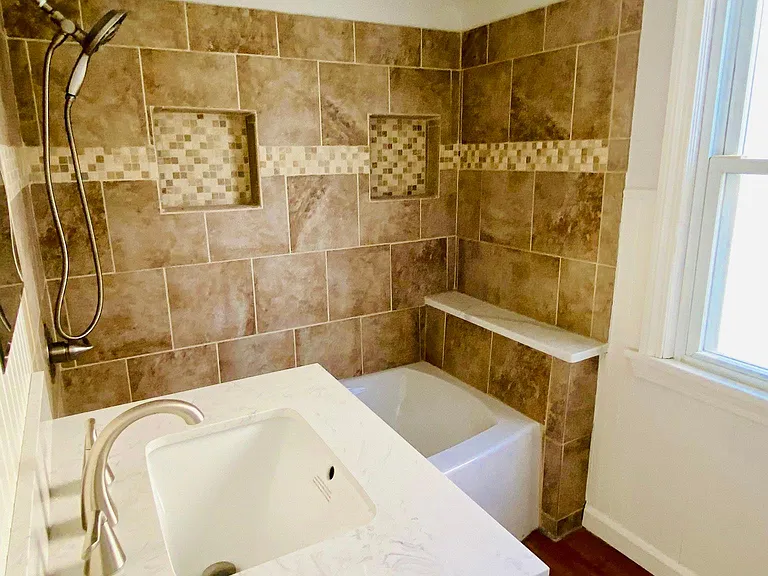 Newly renovated full bath with new vanity, tub and tile surround