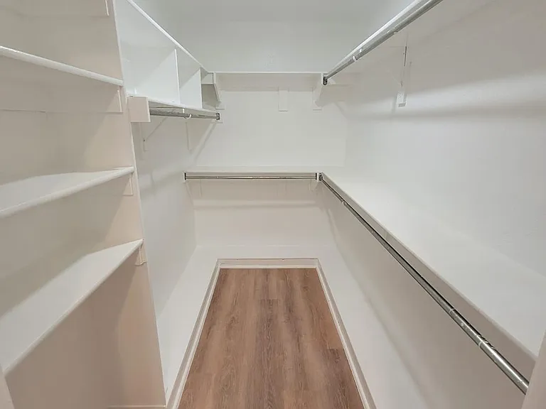 Walk-in closet with built-in shelving and double hanging rods for organized storage and easy access.
