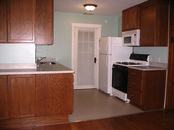 Kitchen w/ gas range, refrigerator, microwave. Door to deck.