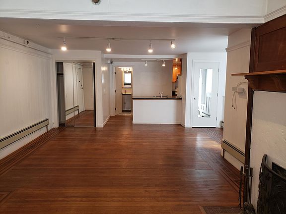 Closets on either side of the room with the kitchen counter in the center and bath in the background.