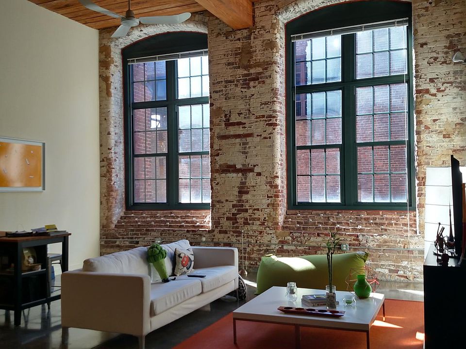 Living room with stunning tall windows, exposed brick, and e