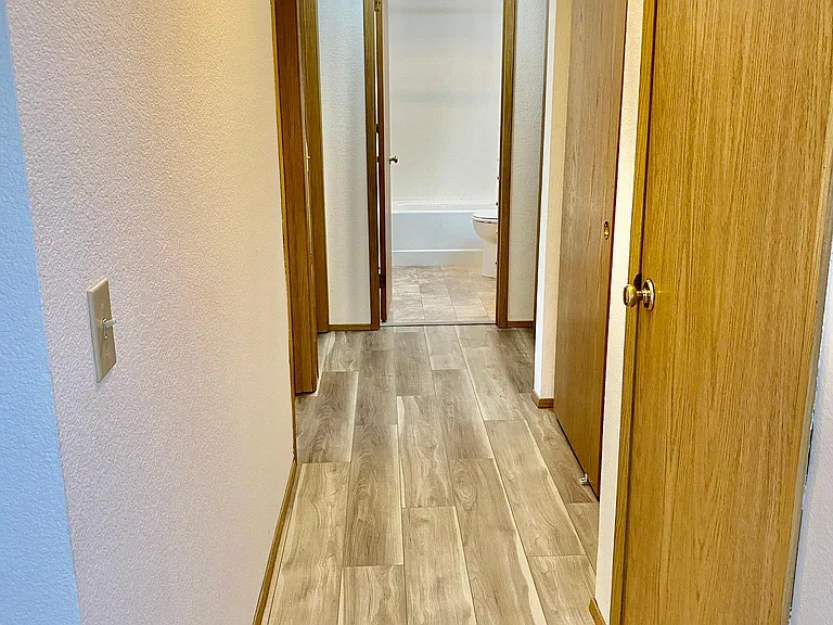 The hallway, looking towards the bathroom. Two bedroom doors on the left.