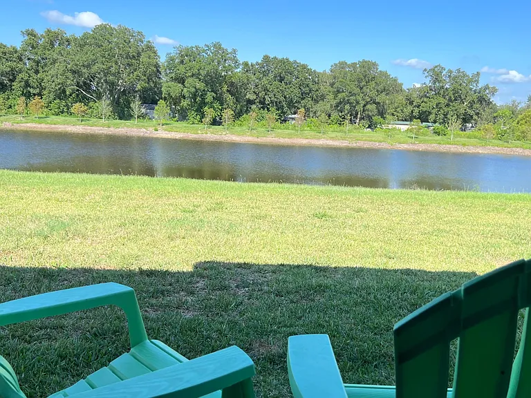 Peaceful backyard view overlooking a pond with open green space and shadeideal for relaxing outdoors.