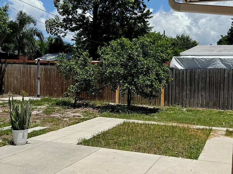 Backyard with fruit trees and planting bed for veggies/flowers and a rain barrel.