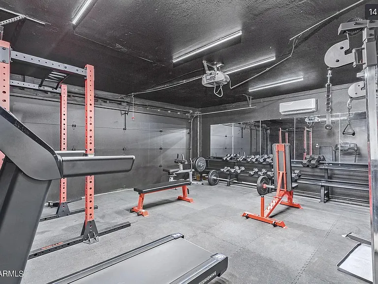 Dedicated home gym area with rubber flooring, mirrored wall, and space for free weights and strength equipment.