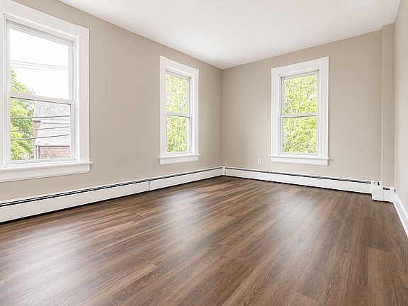 Large bedroom with two windows, new flooring, fresh paint, and good natural light.