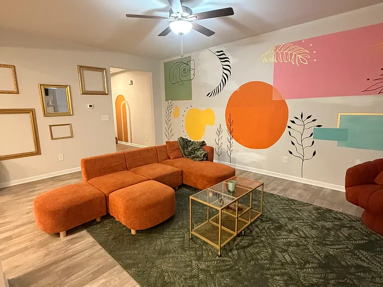 Inviting living room with a sectional seating area, ceiling fan, and wood-look flooringideal for relaxing or hosting.