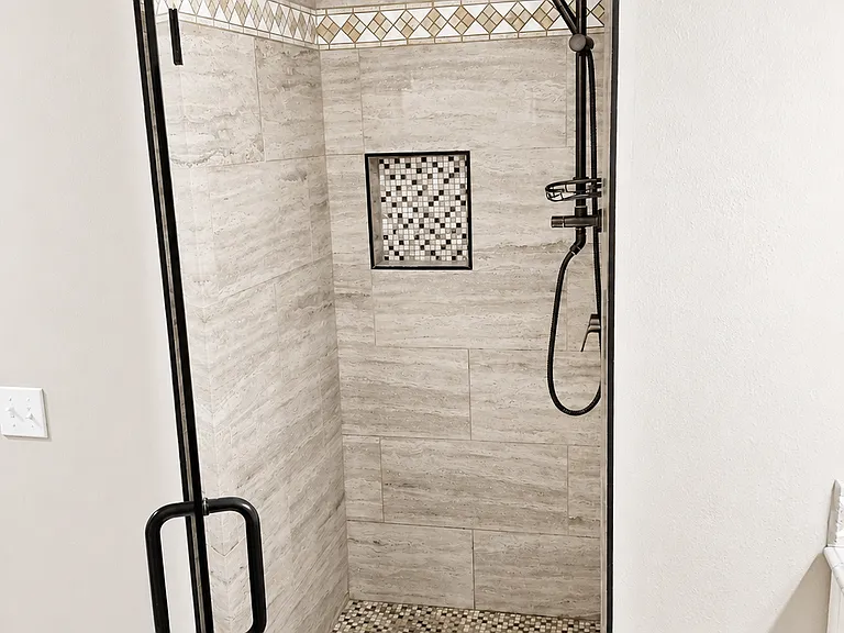 Updated walk-in shower with tile surround, glass door, rainfall shower head, and built-in niche.