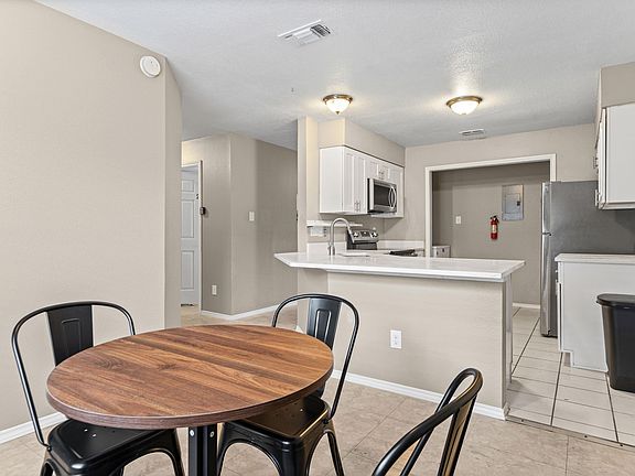 Eat-in kitchen with breakfast bar, ample cabinet storage, and stainless steel appliances, open to a small dining nook.