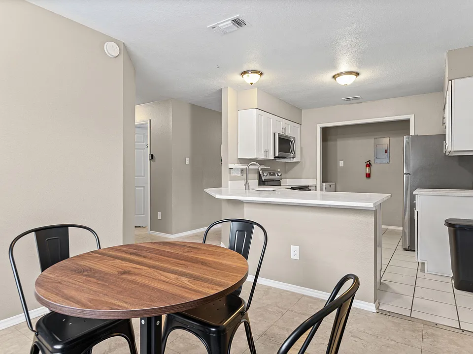 Eat-in kitchen with breakfast bar, ample cabinet storage, and stainless steel appliances, open to a small dining nook.