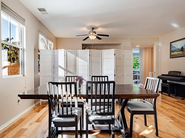 Dedicated dining area with a large table, hardwood floors, and natural light from oversized windows for everyday meals.