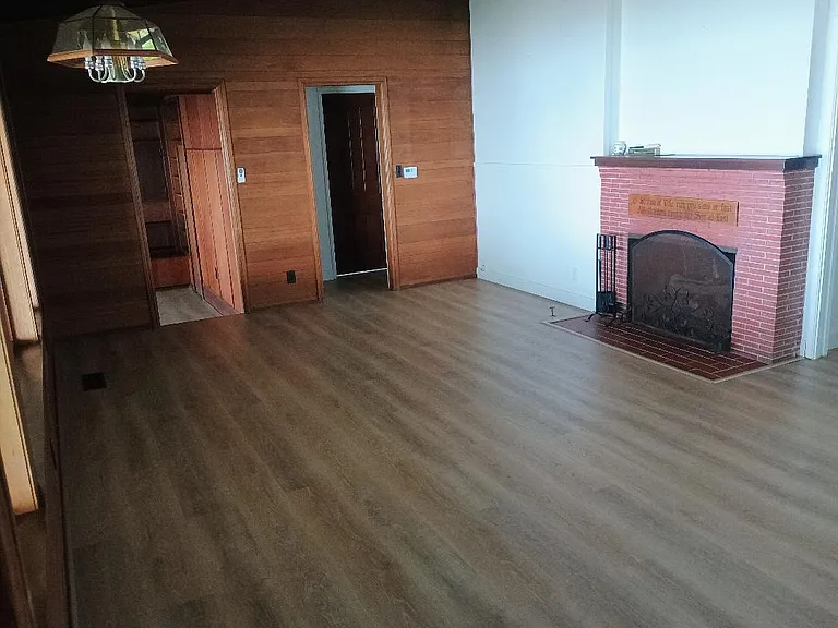 Living Room - Wood Burning/Gas Fireplace on Right, Doorway to Bathroom, Bedrooms At Center, Doorway To Den Upper Left