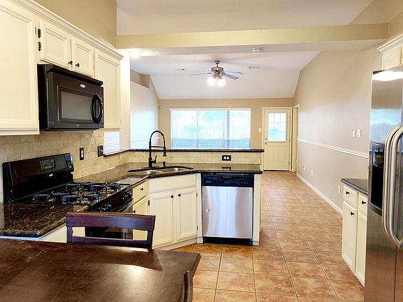 Kitchen features granite countertops and appliances including stainless steel refrigerator