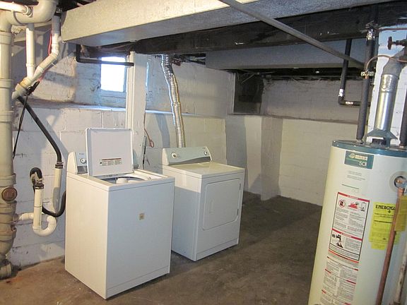 Unfinished basement with washer and dryer for 1st floor apartment only. HVAC and hot water heaters for duplex and additional storage area.