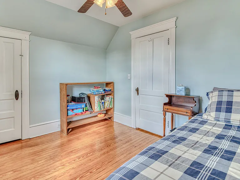 South-facing front bedroom has twin size bed, bedside table, dresser, ceiling fan & closet. This bedroom also has dedicated work space with desk and chair.