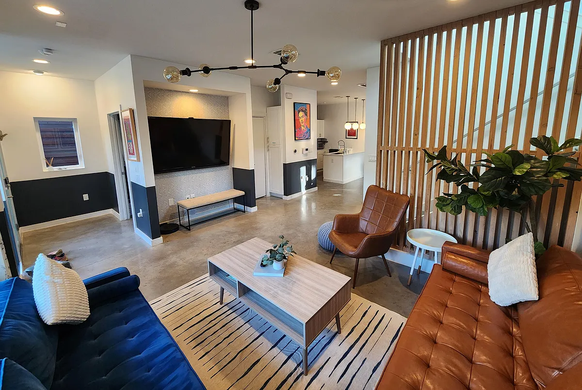Spacious living room with 70 inch Sharp Aquos TV and Roku Express, opens to dining room and kitchen. - 1407 Holly St