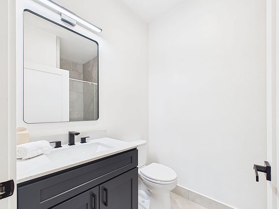 Updated bathroom with a wide vanity, sleek black fixtures, and ample mirror space with overhead lighting.