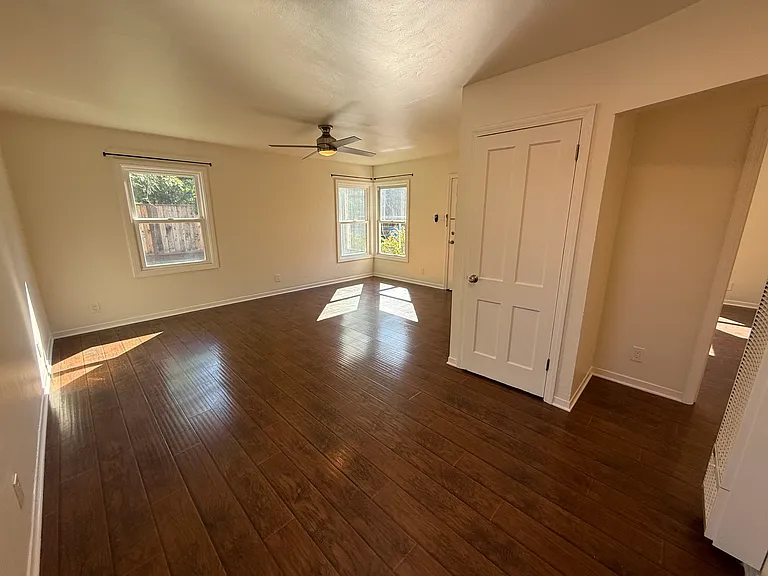 Bright, airy living room features multiple windows and hard surface flooring throughout.