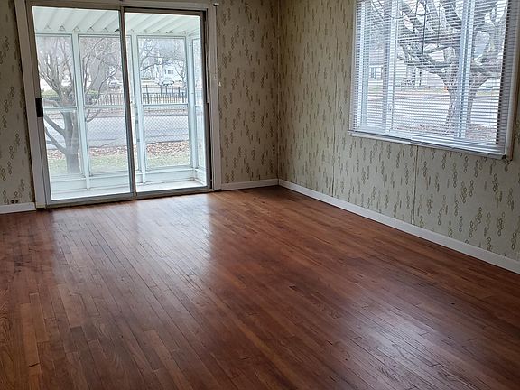 Living room, front door is next to window. Doors lead out to sun room.