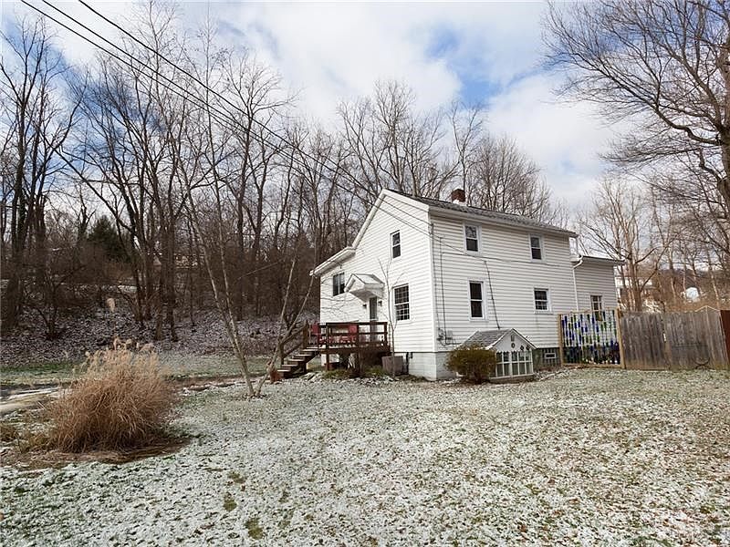 Two stories with vinyl siding. There is a small greenhouse that connects near the basement door.