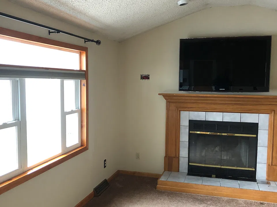 Family-room with gas insert fireplace, large window looking to yard. Large TV over fireplace also included.