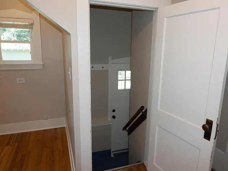 The view through the back kitchen door down the stairs to the back door landing. The kitchen nook is on the left.