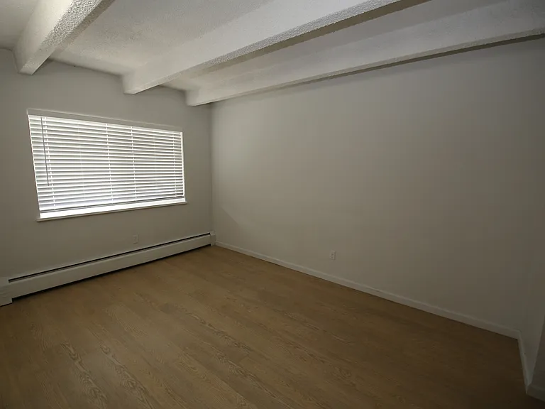 Bright, spacious room with large window and elegant wooden flooring, perfect for a cozy living space.