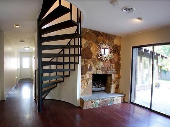 A look at part of the Den w/cool stone fireplace & spiral staircase leading to 2 other bedrooms & bathroom.